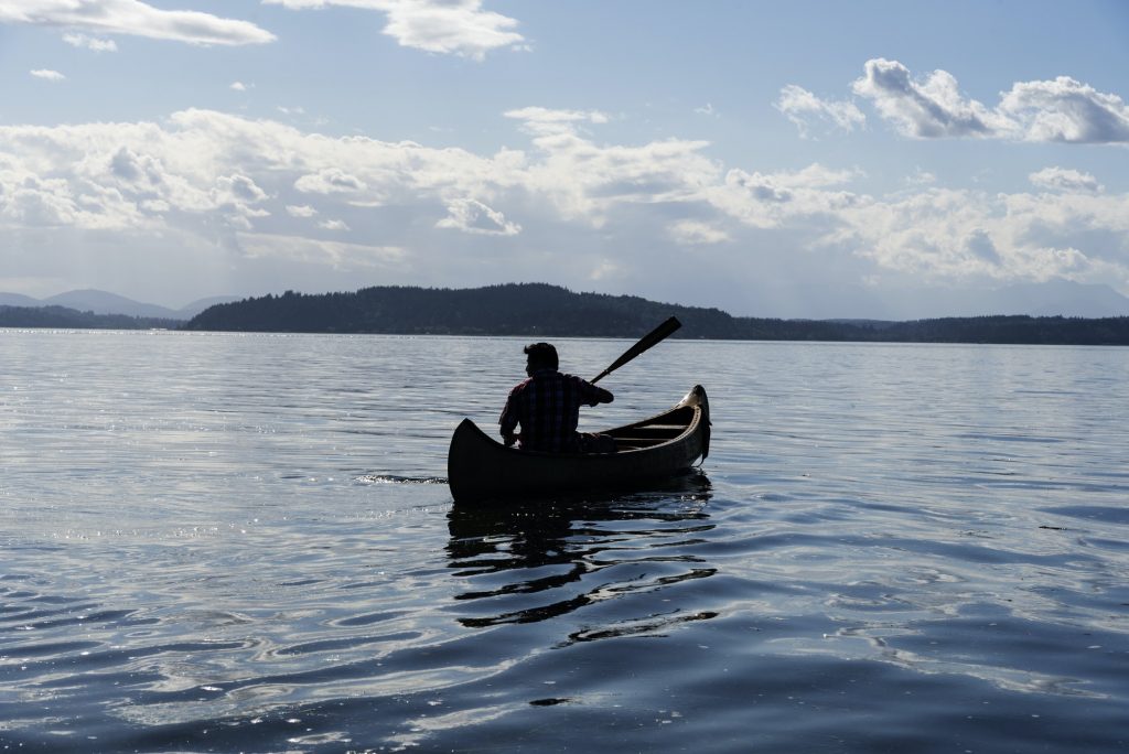 Native American canoe paddling out to distant islands