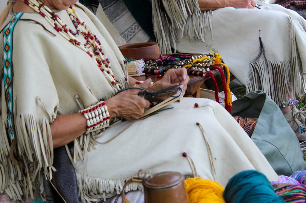 Native American Indians making string jewelry